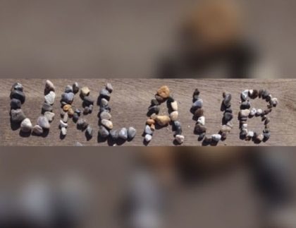 Schriftzug „Urlaub“ aus Steinen am Strand